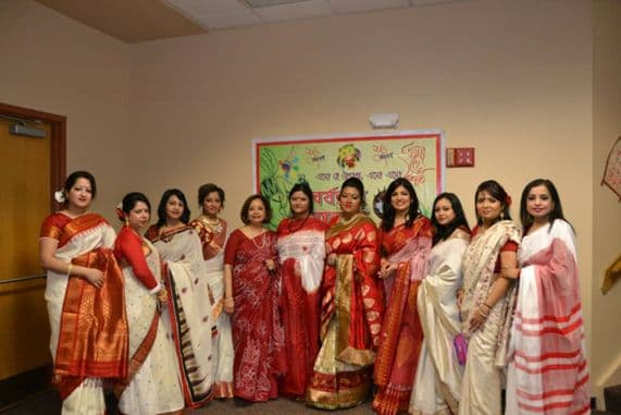 Community members in red and white saris at a Pohela Boishakh gathering